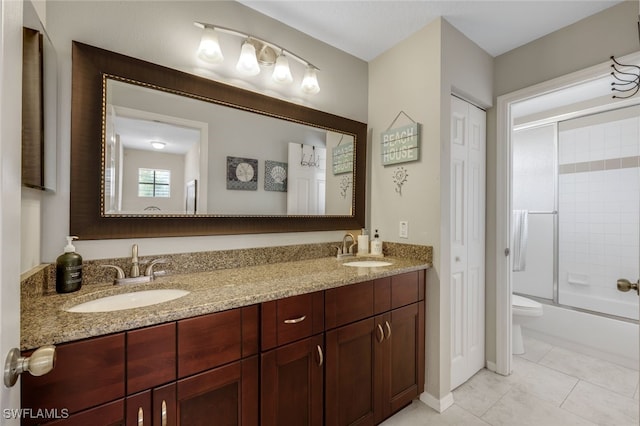 full bathroom with tile patterned flooring, bath / shower combo with glass door, vanity, and toilet