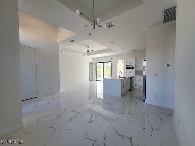 unfurnished living room featuring sink, a raised ceiling, and ceiling fan with notable chandelier