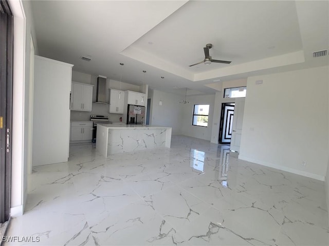 unfurnished living room with a tray ceiling, ceiling fan, marble finish floor, and visible vents