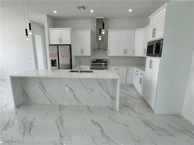 kitchen featuring a center island with sink, stainless steel appliances, hanging light fixtures, sink, and wall chimney range hood