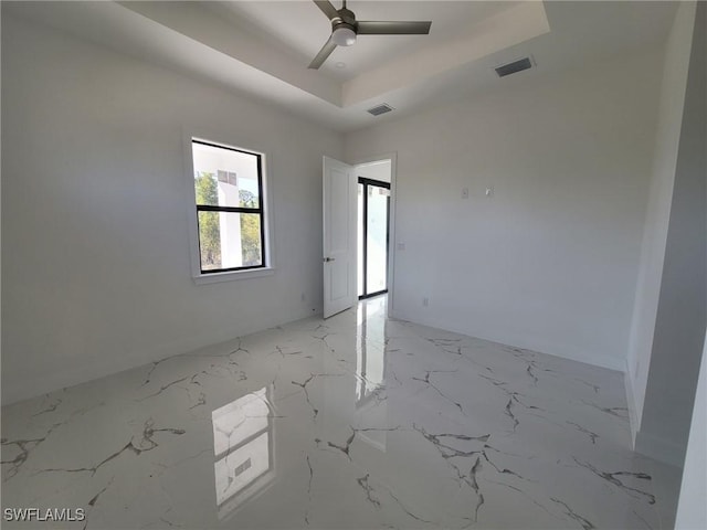 spare room featuring visible vents, a raised ceiling, marble finish floor, and a ceiling fan