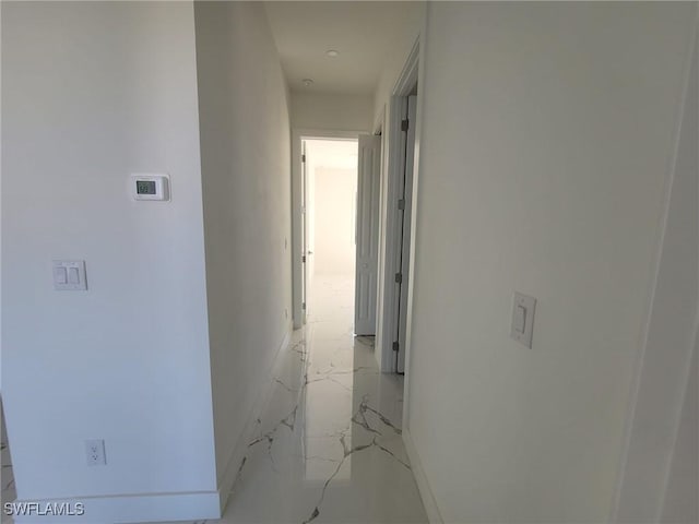 hallway featuring marble finish floor and baseboards