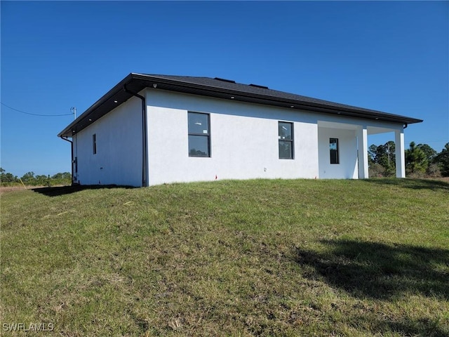 rear view of house featuring stucco siding and a lawn