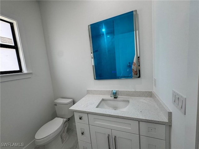 bathroom featuring toilet, vanity, and marble finish floor