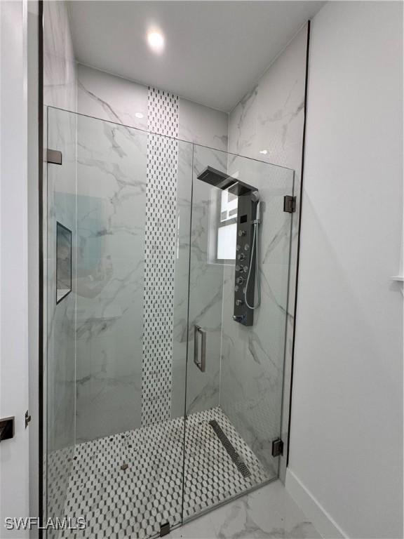 bathroom with a marble finish shower, baseboards, and marble finish floor
