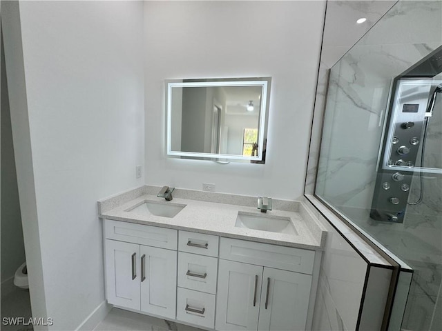 bathroom featuring double vanity, baseboards, a sink, and a marble finish shower
