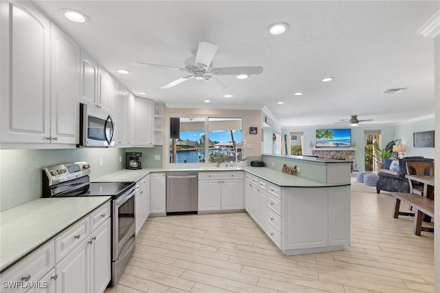 kitchen featuring appliances with stainless steel finishes, a healthy amount of sunlight, white cabinetry, and kitchen peninsula