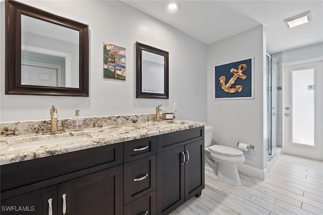 bathroom featuring hardwood / wood-style floors, a shower with shower door, vanity, and toilet