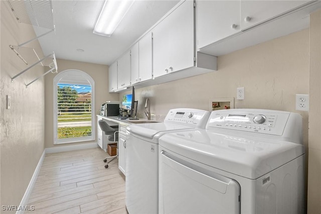 clothes washing area with washing machine and dryer and cabinets