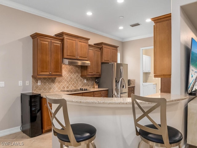 kitchen with stainless steel refrigerator with ice dispenser, a breakfast bar, and kitchen peninsula