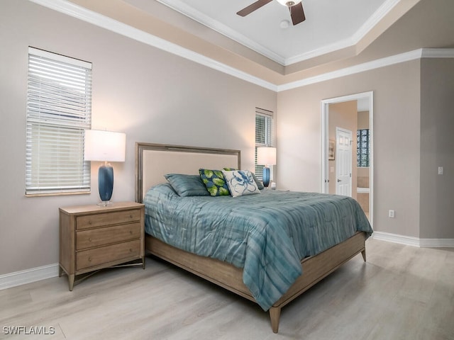 bedroom with crown molding, ceiling fan, ensuite bathroom, a tray ceiling, and light hardwood / wood-style floors