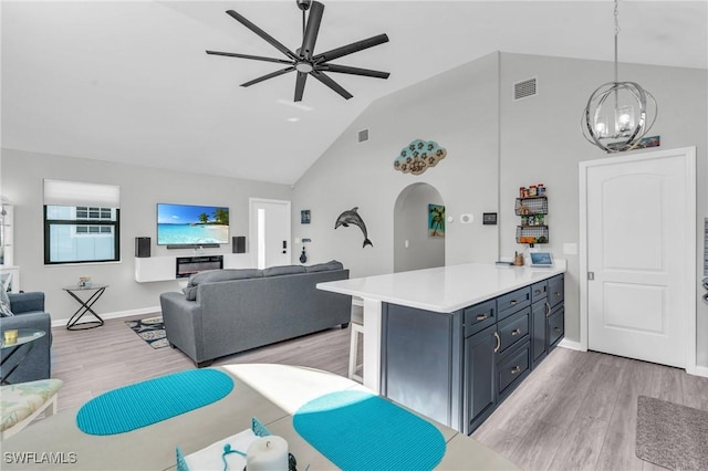 kitchen with arched walkways, pendant lighting, light countertops, open floor plan, and a kitchen bar