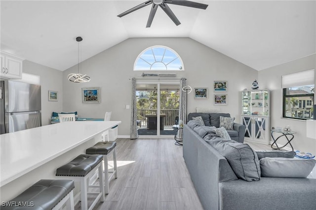 living room featuring a ceiling fan, baseboards, high vaulted ceiling, and light wood finished floors