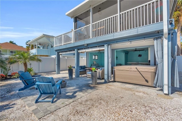 exterior space featuring a balcony, outdoor lounge area, fence, a patio area, and a hot tub