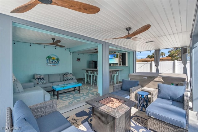 view of patio with fence, outdoor dry bar, a ceiling fan, and an outdoor living space with a fire pit