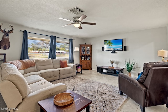 living room featuring a textured ceiling, ceiling fan, and light tile patterned floors