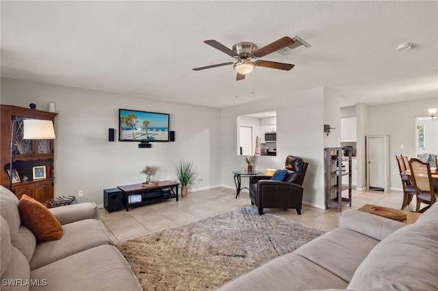 living room featuring ceiling fan with notable chandelier, a textured ceiling, and light tile patterned floors