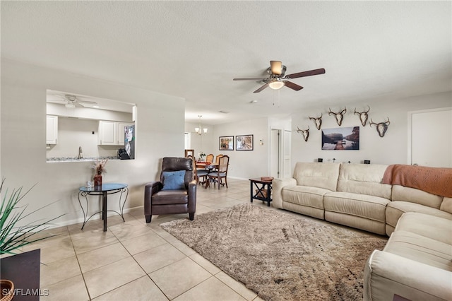 living room with ceiling fan with notable chandelier, a textured ceiling, and light tile patterned floors