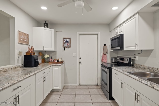 kitchen with stainless steel electric stove, ceiling fan, white cabinetry, light tile patterned flooring, and sink