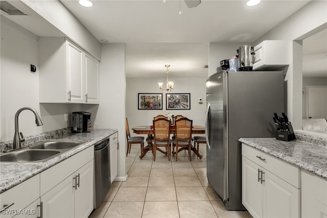 kitchen with sink, stainless steel appliances, white cabinetry, hanging light fixtures, and a chandelier