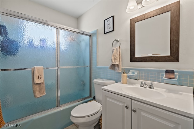 full bathroom with vanity, toilet, shower / bath combination with glass door, and tile walls