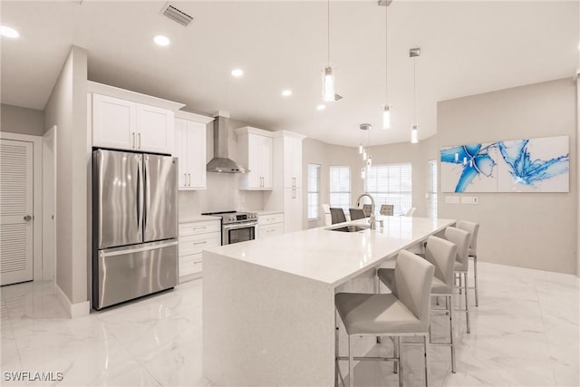 kitchen with white cabinetry, appliances with stainless steel finishes, wall chimney range hood, and sink