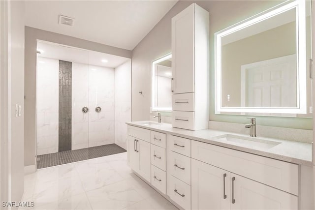 bathroom with tiled shower and vanity