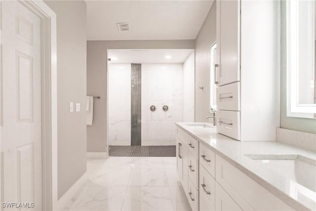 bathroom with tiled shower and vanity