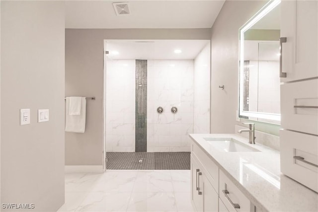 bathroom with a tile shower and vanity