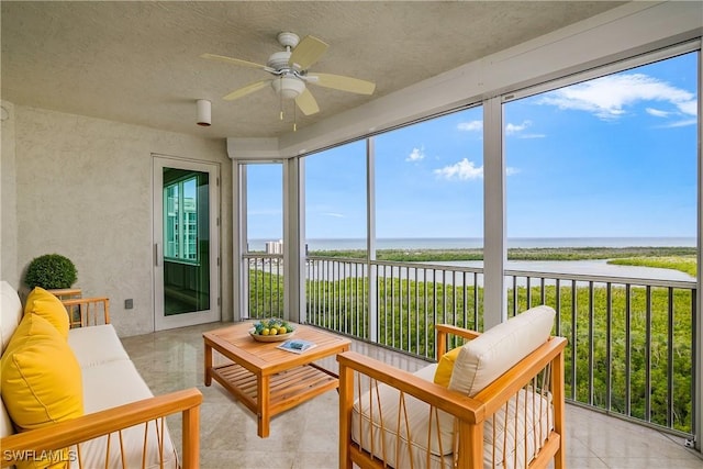 sunroom / solarium featuring ceiling fan, a water view, and plenty of natural light