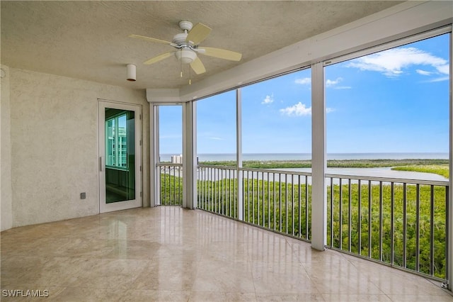 unfurnished sunroom with ceiling fan and a water view