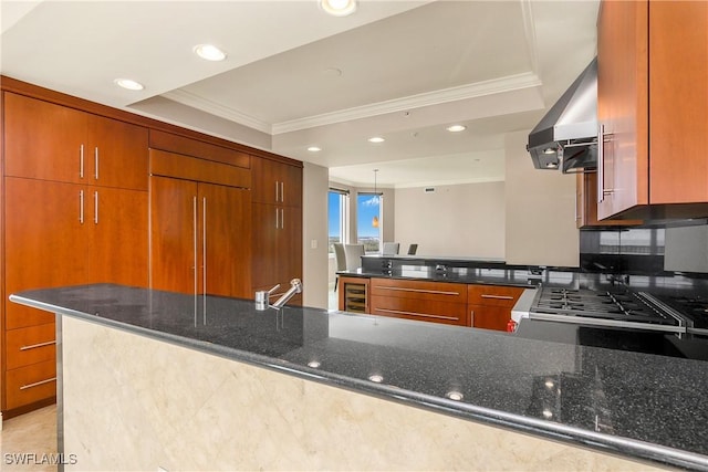 kitchen featuring paneled refrigerator, dark stone countertops, ventilation hood, kitchen peninsula, and a tray ceiling