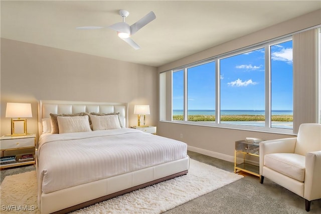 carpeted bedroom with a water view and ceiling fan