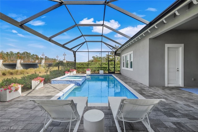 view of pool with glass enclosure, a patio area, and an in ground hot tub