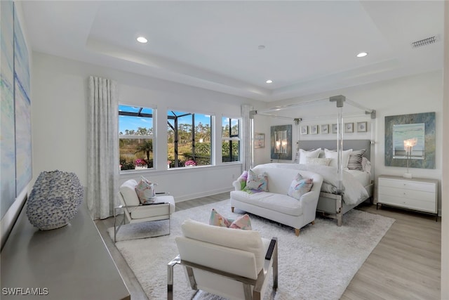 bedroom with a tray ceiling and light hardwood / wood-style flooring