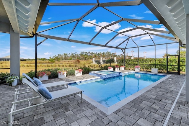 view of pool with a patio, glass enclosure, and an in ground hot tub