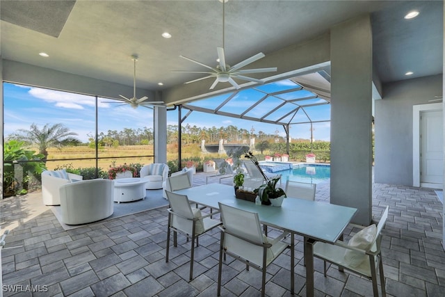 view of patio with ceiling fan and glass enclosure