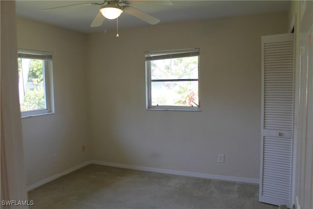 carpeted spare room featuring ceiling fan and a healthy amount of sunlight