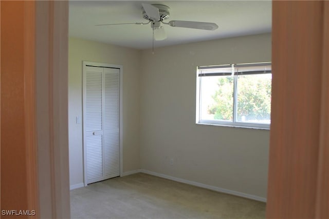 unfurnished bedroom with ceiling fan, a closet, and light carpet