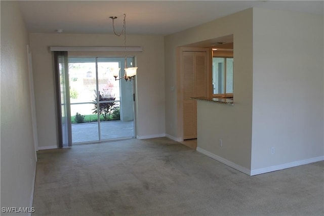 carpeted spare room featuring an inviting chandelier