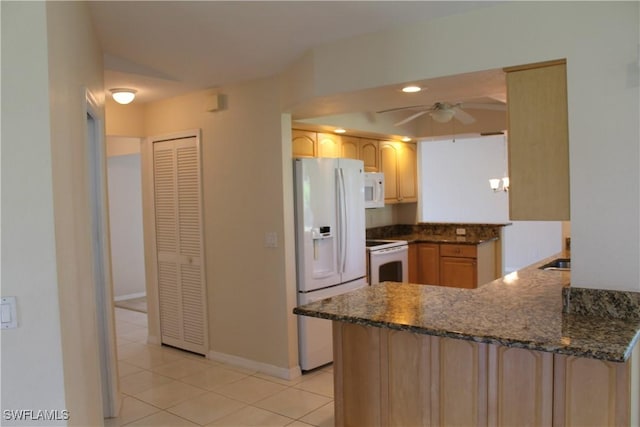 kitchen featuring white appliances, ceiling fan, light tile patterned floors, kitchen peninsula, and dark stone counters