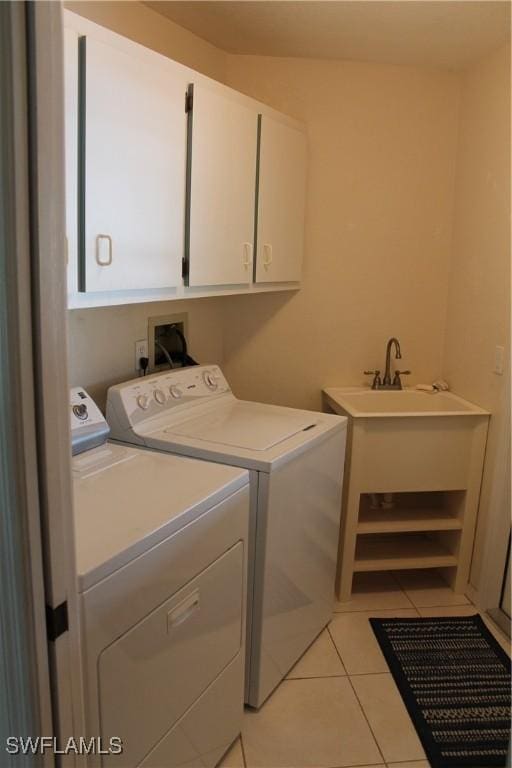 laundry area with washing machine and dryer, light tile patterned flooring, and cabinets