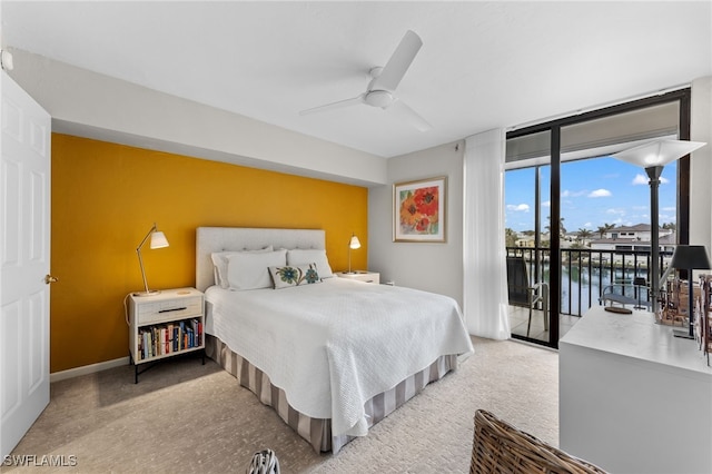 bedroom featuring ceiling fan, a wall of windows, light carpet, a water view, and access to exterior