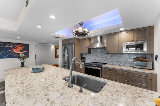 kitchen featuring sink, stainless steel appliances, light stone counters, and wall chimney exhaust hood