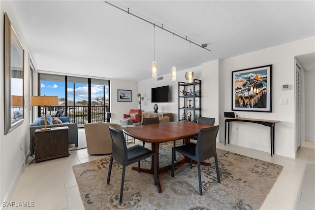 dining space featuring rail lighting, light tile patterned flooring, and floor to ceiling windows