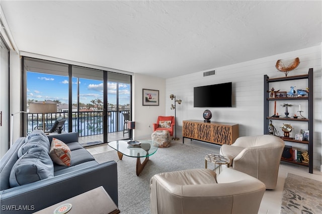 living room with a textured ceiling, light tile patterned floors, and floor to ceiling windows