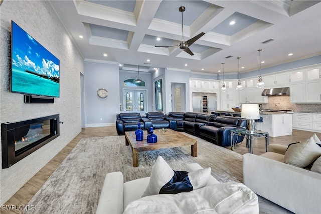 living room with french doors, ornamental molding, a fireplace, and light hardwood / wood-style flooring