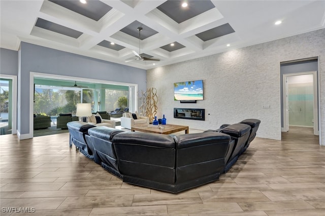 living room featuring ceiling fan, a wealth of natural light, beamed ceiling, and coffered ceiling