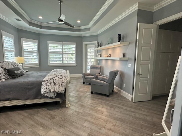 bedroom featuring ceiling fan, light wood-type flooring, a tray ceiling, and ornamental molding