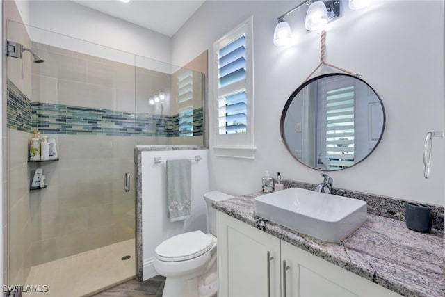 bathroom featuring toilet, a shower with door, and vanity